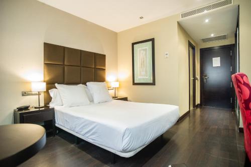 a hotel room with a large bed and a chair at AZZ Asturias LangreHotel & Spa in Langreo