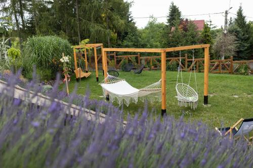 a swing set in a garden with purple flowers at Czereśniowe Wzgórze Sandomierz jakuzzi in Sandomierz