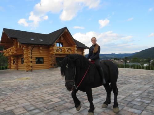 a man riding a horse in front of a log cabin at Bucovina Exclusiv in Vama
