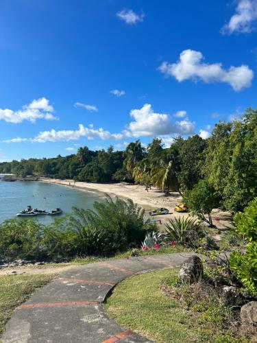 a path leading to a beach with boats in the water at Kaz Caraïbes spacieuse, accès piscine et plage - Résidence in Sainte-Luce