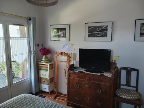- une chambre avec une télévision sur une commode en bois et un lit dans l'établissement Ty Glaz, à Kerbors