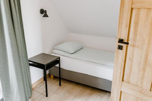a small bed with a table next to a door at Dobre Kąty całoroczne domki in Kąty Rybackie