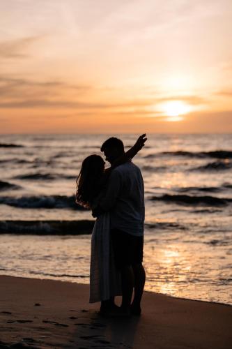 a couple standing on the beach at sunset at Dobre Kąty całoroczne domki in Kąty Rybackie