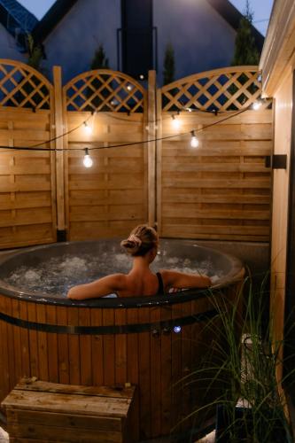 a woman sitting in a hot tub in a backyard at Dobre Kąty całoroczne domki in Kąty Rybackie