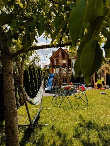 a hammock and a playground in a yard at Dobre Kąty całoroczne domki in Kąty Rybackie