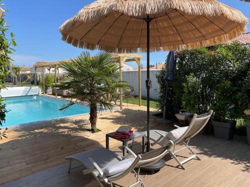 un patio avec deux chaises et un parasol à côté d'une piscine dans l'établissement Villa de charme piscine chauffée St Pierre Oléron, à Saint-Pierre-dʼOléron