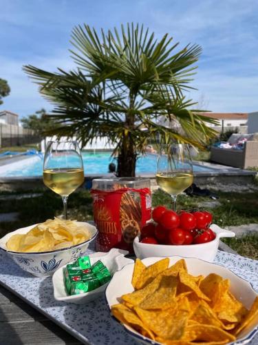 une table avec des frites et des verres de vin et une table avec de la nourriture dans l'établissement Villa de charme piscine chauffée St Pierre Oléron, à Saint-Pierre-dʼOléron