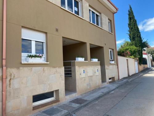 a building with two windows and potted plants on it at VuT QUINTA LA LEGUA in Quintanadueñas