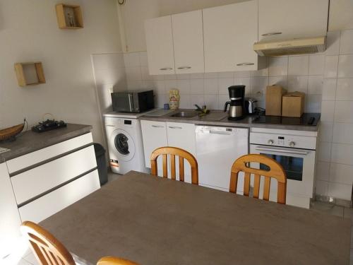 une cuisine avec des armoires blanches et une table et des chaises dans l'établissement les elmes 3, à Banyuls-sur-Mer