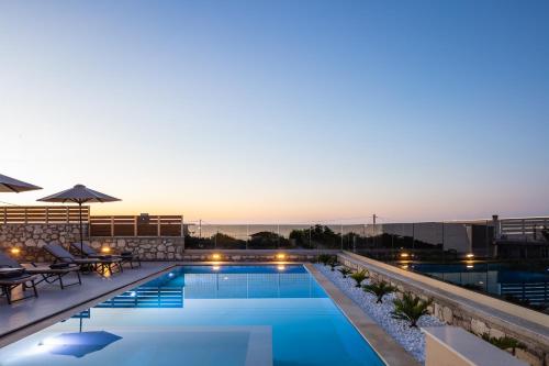 a pool on the roof of a building with a sunset at Villa Arismari in Tria Monastiria