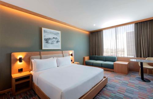 a hotel room with a bed and a couch at Hilton Garden Inn Guadalajara Airport in Guadalajara