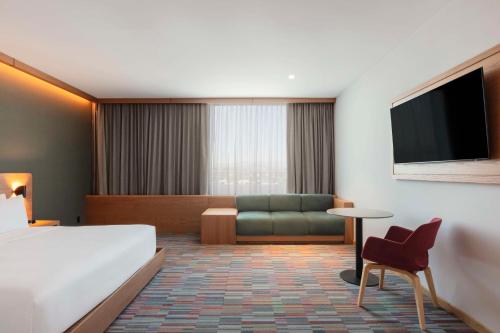 a hotel room with a bed and a couch at Hilton Garden Inn Guadalajara Airport in Guadalajara
