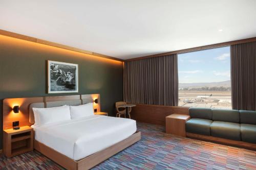 a hotel room with a bed and a couch at Hilton Garden Inn Guadalajara Airport in Guadalajara