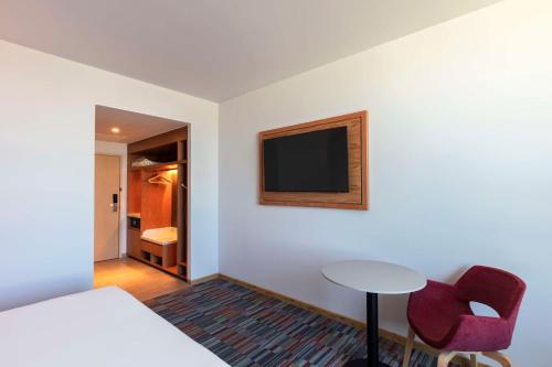 a room with a bed and a table and a tv at Hilton Garden Inn Guadalajara Airport in Guadalajara