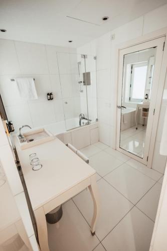 a white bathroom with a sink and a mirror at Palacio Avenida in Palma de Mallorca