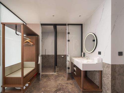 a bathroom with a sink and a shower and a mirror at Hilton Garden Inn Taiyuan Binhe in Yangjiabu