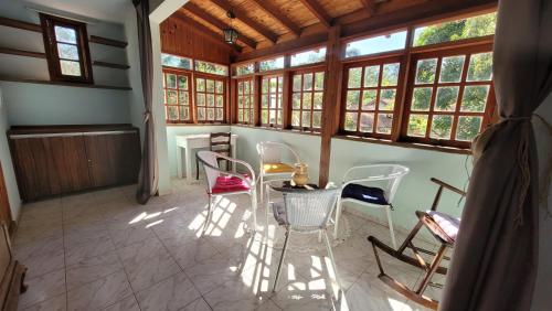 a room with chairs and a table and windows at Sitio CANTOS DA FLORESTA in Mairinque