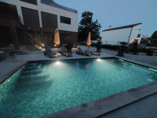 a swimming pool with chairs and umbrellas next to a building at Villa Sunce Funtana in Funtana