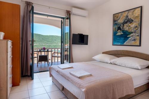a bedroom with a bed and a balcony with a table at Villa Piccolotti in Neum