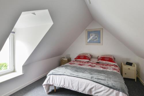 - une chambre mansardée avec un lit et des oreillers rouges dans l'établissement L'Écrin de Douvres - Charmante maison pour 2p, à Douvres-la-Délivrande