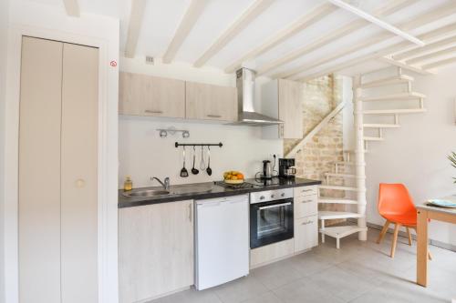 une cuisine blanche avec un évier et une cuisinière dans l'établissement L'Écrin de Douvres - Charmante maison pour 2p, à Douvres-la-Délivrande