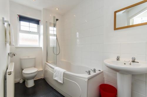 a white bathroom with a sink and a tub and a toilet at Sawadee Apartments in Warwick