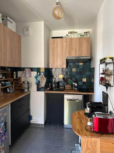 une cuisine avec des armoires en bois et une table à l'intérieur dans l'établissement Appartement confortable et parking, à Asnières-sur-Seine