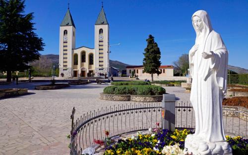 a statue of a man standing in front of a church at Apartmani Portina in Baćina