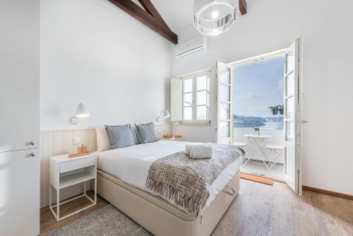 a white bedroom with a bed and a large window at GuestReady - Port Studio 1 in Vila Nova de Gaia