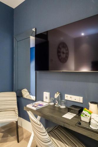 a room with a table and chairs and a clock at Abba San Sebastián Hotel in Donostia-San Sebastián