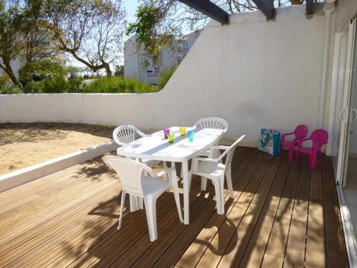 une table et des chaises blanches sur une terrasse en bois dans l'établissement Maison refaite à neuf proche plage, 3 pièces, 6 couchages, jardin privé, parking inclus - FR-1-224C-156, à Saint-Jean-de-Monts