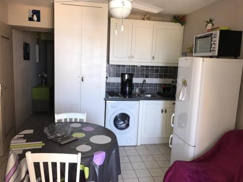 une cuisine avec une table et un réfrigérateur blanc dans l'établissement Studio cabine avec loggia, 4 pers, mer à 50m, commerces à 150m, proche Aqualand - FR-1-81-231, à Port-Leucate