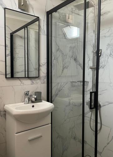a white bathroom with a sink and a shower at Vasilios Marinos Rooms in Korinthos
