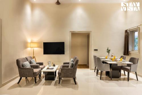 a dining room with a table and chairs and a tv at StayVista's Ashwamedha Manor - Mountain-Side Luxury Retreat with Outdoor Pool, Jacuzzi, Spa & Steam Room, and Indoor Activities in Karjat
