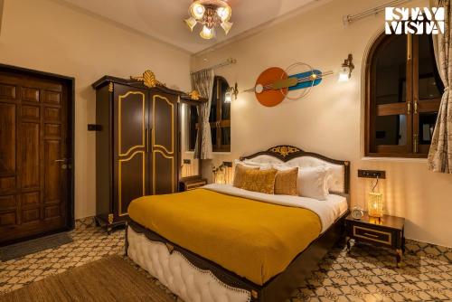 a bedroom with a large bed with a yellow blanket at StayVista's Ashwamedha Manor - Mountain-Side Luxury Retreat with Outdoor Pool, Jacuzzi, Spa & Steam Room, and Indoor Activities in Karjat