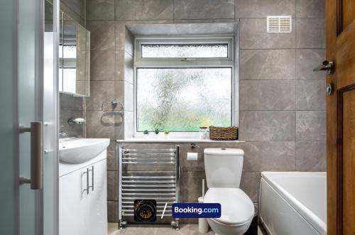 a bathroom with a toilet and a sink and a window at Cosy 3-Bed House l Garden l Free Parking l Stretford l Sleeps 7 l Book today with The Cosy Corner Nationwide in Manchester