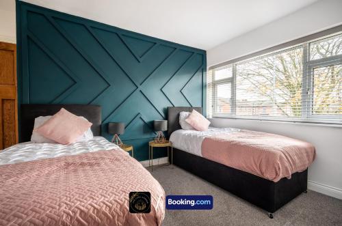 a bedroom with two beds and a blue wall at Cosy 3-Bed House l Garden l Free Parking l Stretford l Sleeps 7 l Book today with The Cosy Corner Nationwide in Manchester