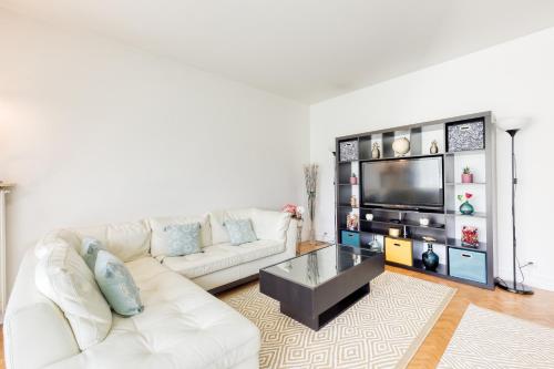 ein Wohnzimmer mit einem weißen Sofa und einem Fernseher in der Unterkunft Disponible - 5mn Paris - Gare à Pied - Jardin Terrasse - 6 pers - Centre Ville - Proche tous Commerces et transports - Wifi in Maisons-Alfort