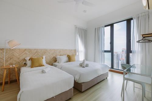 two beds in a hotel room with a large window at The Jazz Serviced Suites in Tanjong Tokong