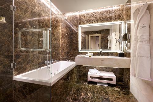 a bathroom with a tub and a sink and a mirror at The First Arte - Preferred Hotels & Resorts in Rome