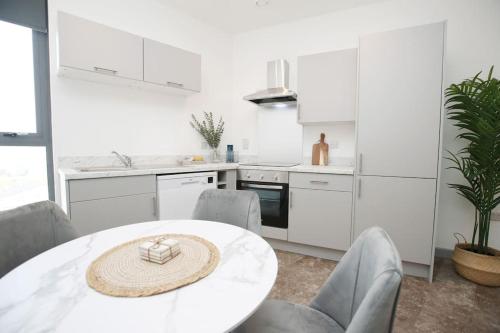 a white kitchen with a white table and chairs at High Point 1 Bedroom Apartment in Bradford