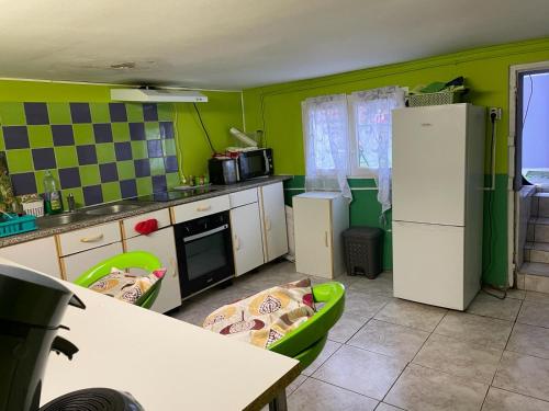 cocina con paredes verdes y nevera blanca en Logement entrée indépendant, sous sol éclairé, cuisine, SDB WC, jardin, en Belle-Église