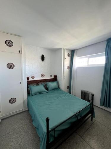 a bedroom with a green bed with a window at Beach-Appartment Marbel at Malabata Beach in Tangier