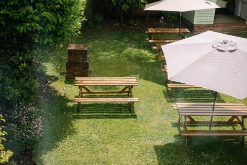 a row of benches with an umbrella in the grass at Hewitt's Restaurant & Rooms in Newport