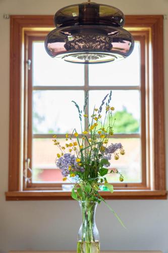 a glass vase with flowers in front of a window at Kackelstugan in Borgholm