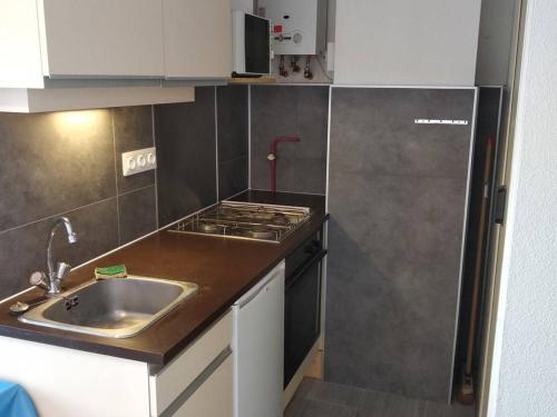 une petite cuisine avec un évier et une cuisinière dans l'établissement Appartement T2 avec Tennis, Piscine et Parking à 100m de la Mer - Cap d'Agde - FR-1-607-15, au Cap d'Agde