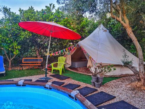 a red umbrella and a tent next to a pool at Bell Tent Lovers by Casa das Artes in Luz de Tavira