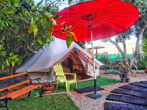 a tent with a chair and a red umbrella at Bell Tent Lovers by Casa das Artes in Luz de Tavira