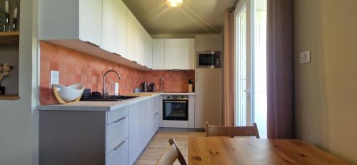 une cuisine avec des armoires blanches et une table en bois dans l'établissement Appartement 2 Queenbed parking clim wifi, à Aix-en-Provence