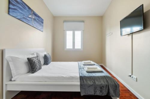a bedroom with a white bed with a tv at A ver o mar rooms - Santa Cruz city center in Santa Cruz
